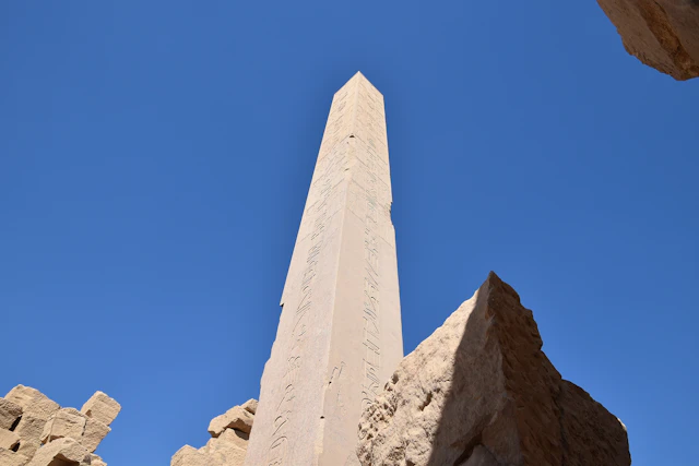 An awe-inspiring view of a towering obelisk at Karnak, its ancient inscriptions etched deep into the polished stone. This monolithic structure, reaching skyward, reflects the architectural mastery and spiritual aspirations of the New Kingdom pharaohs.