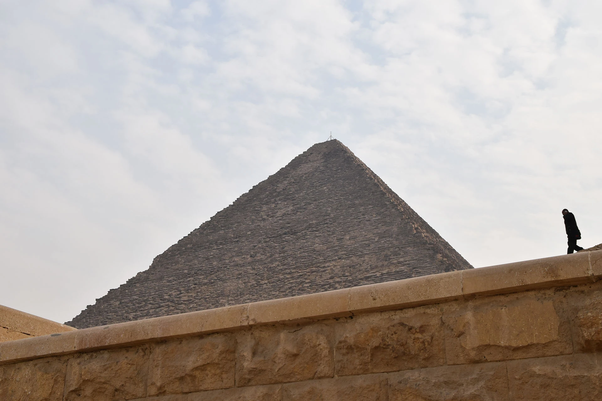 A striking perspective of a pyramid in Giza, where ancient grandeur meets the quiet presence of modern-day visitors.