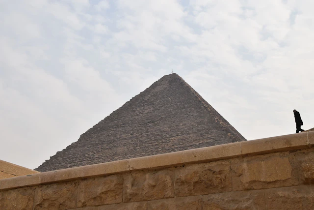 A striking perspective of a pyramid in Giza, where ancient grandeur meets the quiet presence of modern-day visitors.