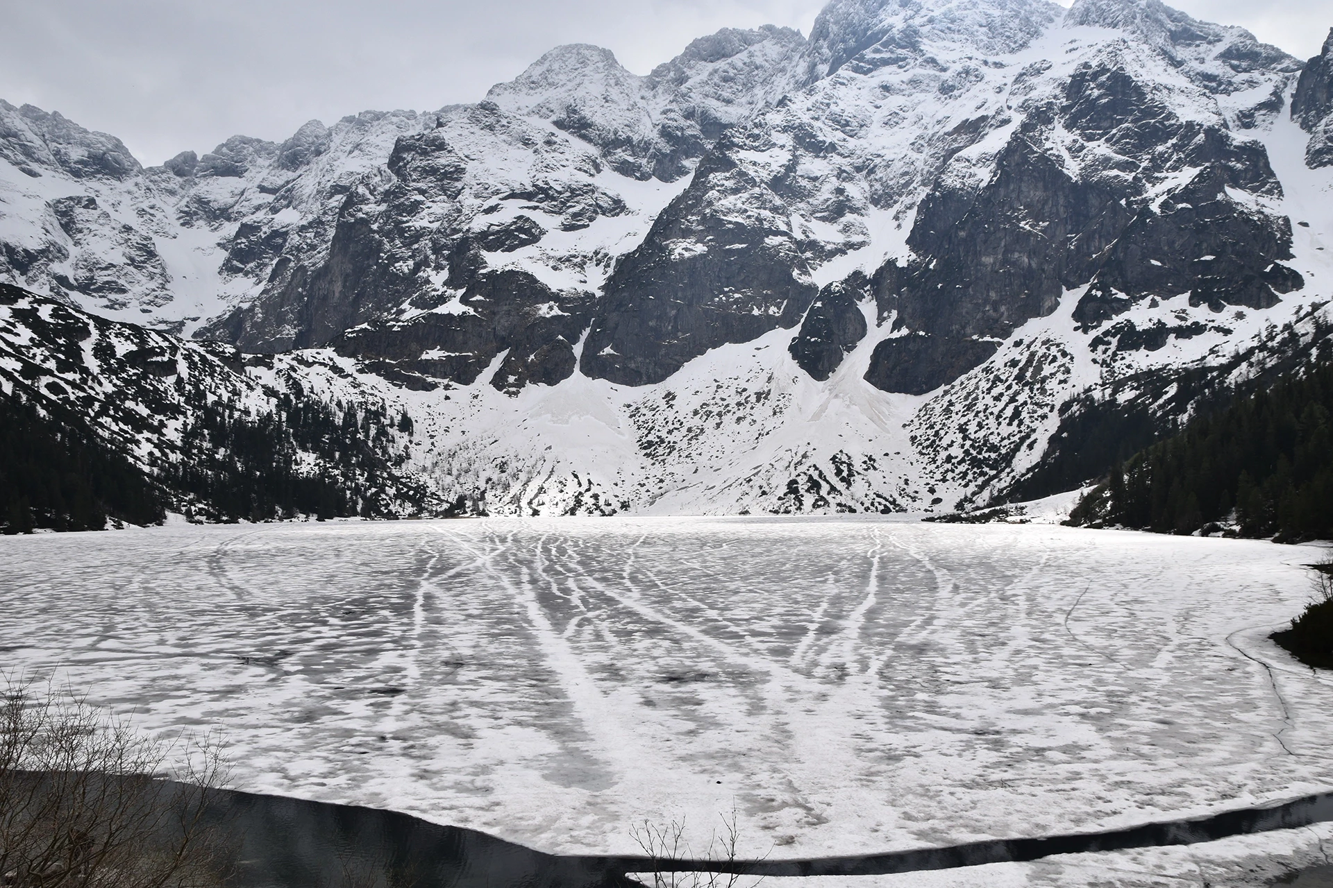 Morskie Oko, a pristine mountain lake nestled in the Tatra Mountains, offers a breathtaking scene of ice-covered waters and dramatic alpine peaks.