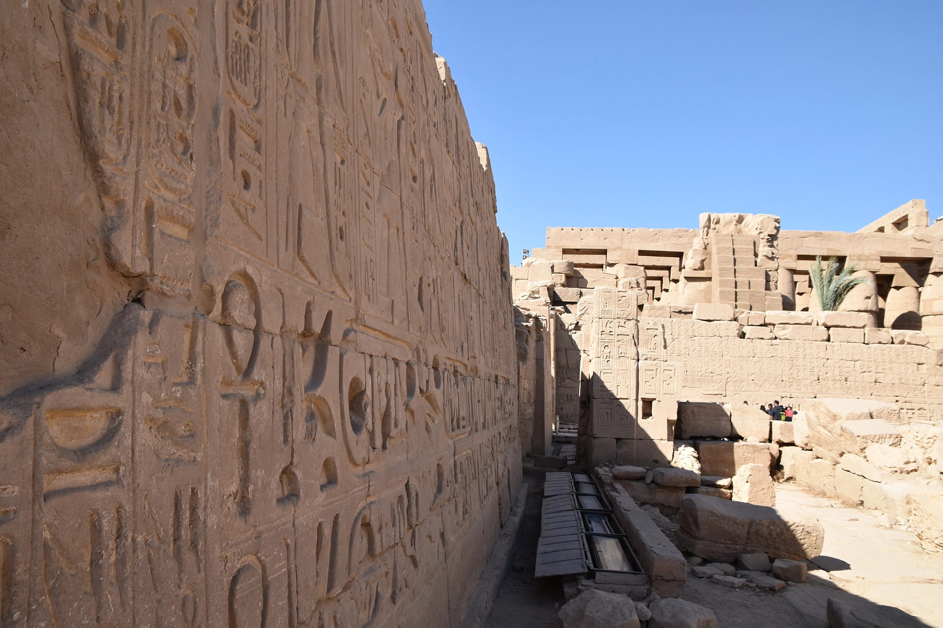 A detailed view of a hieroglyphic-covered wall within Karnak Temple, illustrating sacred symbols and royal decrees. The intricate carvings reflect the temple's role as a central hub for religious and political ceremonies in ancient Thebes.