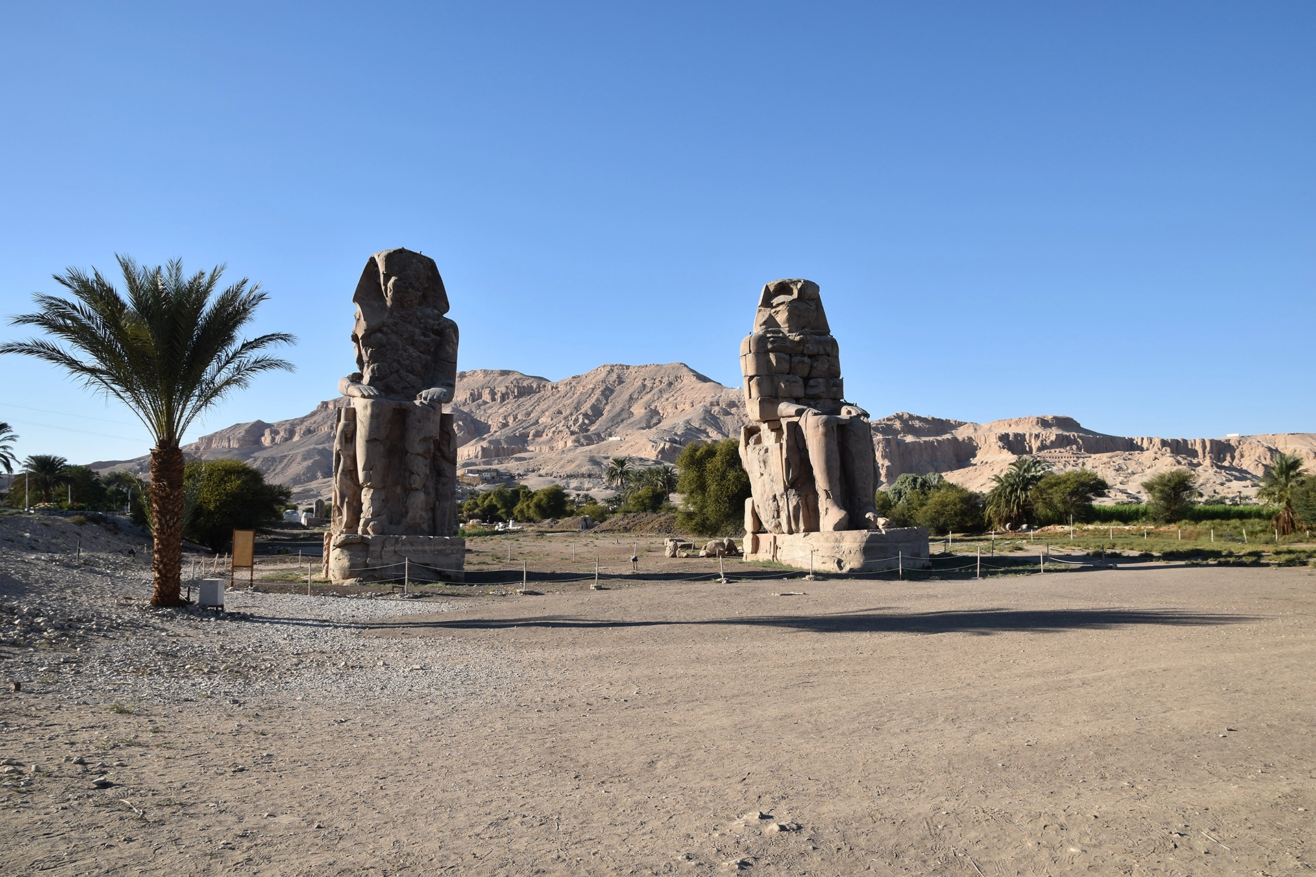 The majestic Colossi of Memnon stand guard over the Theban Necropolis, their weathered faces gazing across the vast desert landscape. These monumental statues, once part of Amenhotep III's mortuary temple, evoke the grandeur and mystery of ancient Egypt.