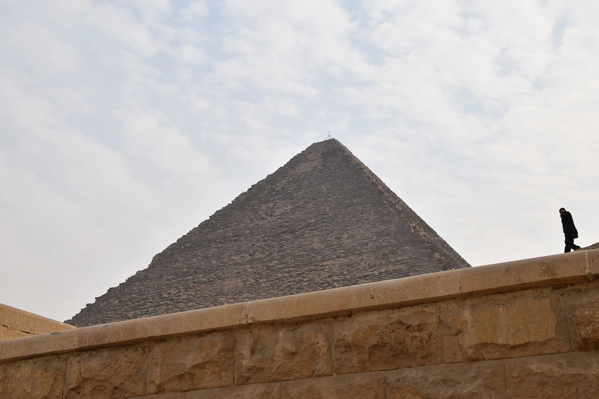 A striking perspective of a pyramid in Giza, where ancient grandeur meets the quiet presence of modern-day visitors.