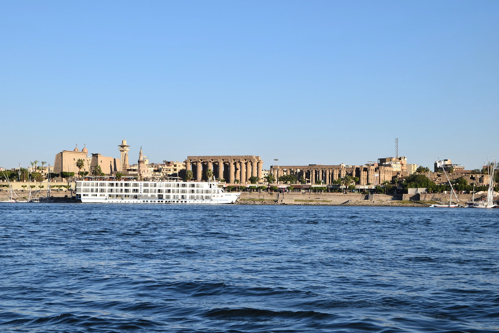 A breathtaking view of Luxor from the Nile River, showcasing the monumental Luxor Temple with its grand columns. In the background, the Mosque of Abu Haggag adds a spiritual touch, blending Islamic heritage with the ancient grandeur of this historic city.