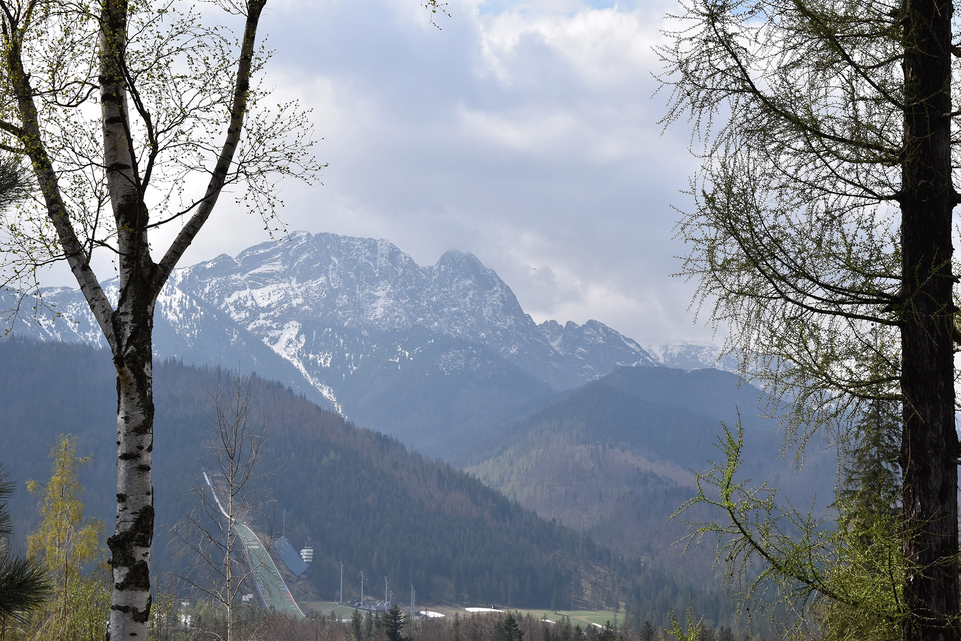 A breathtaking view of the Tatra Mountains from Zakopane, with the Wielka Krokiew ski jump nestled among the scenic forested slopes.