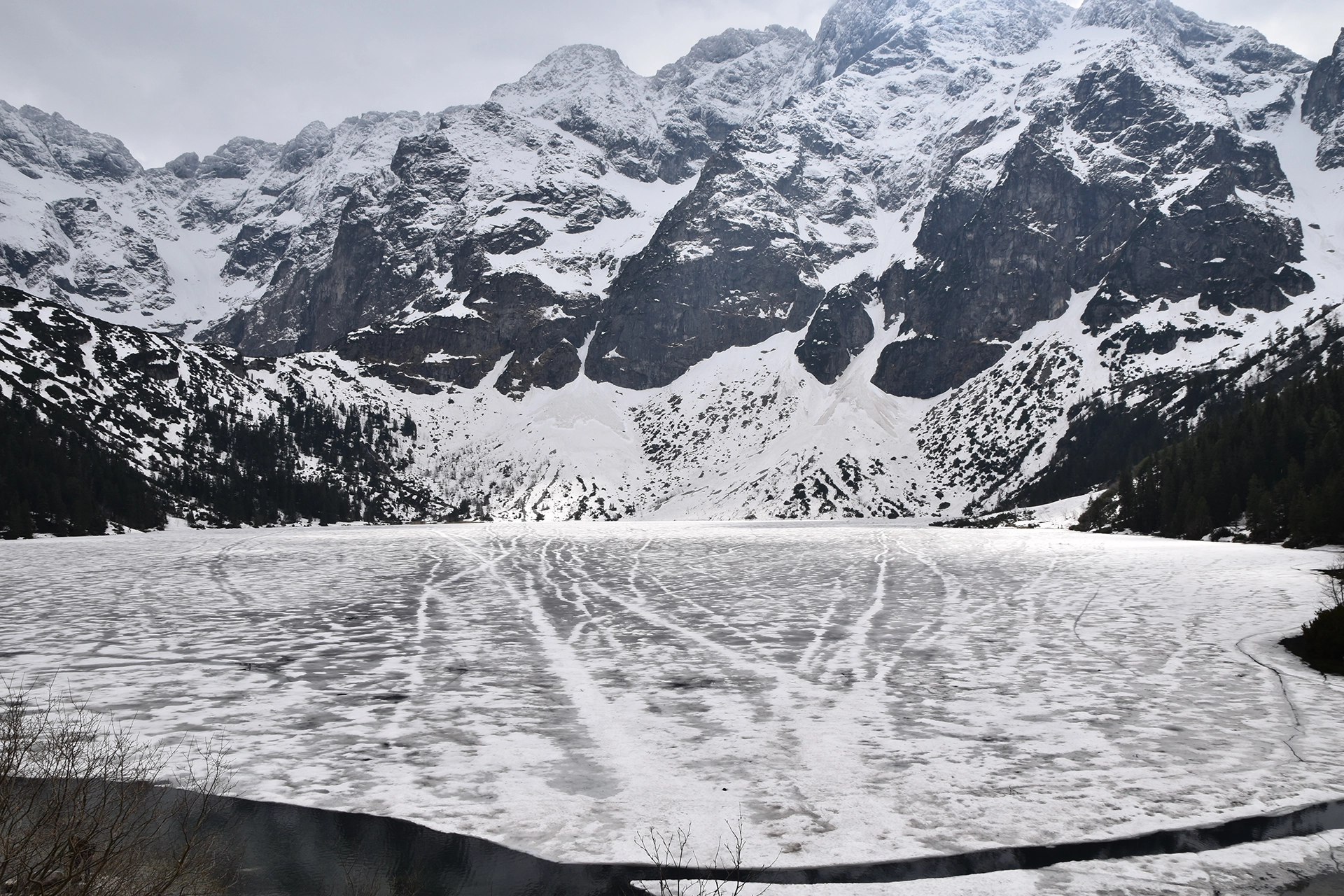 Morskie Oko, a pristine mountain lake nestled in the Tatra Mountains, offers a breathtaking scene of ice-covered waters and dramatic alpine peaks.